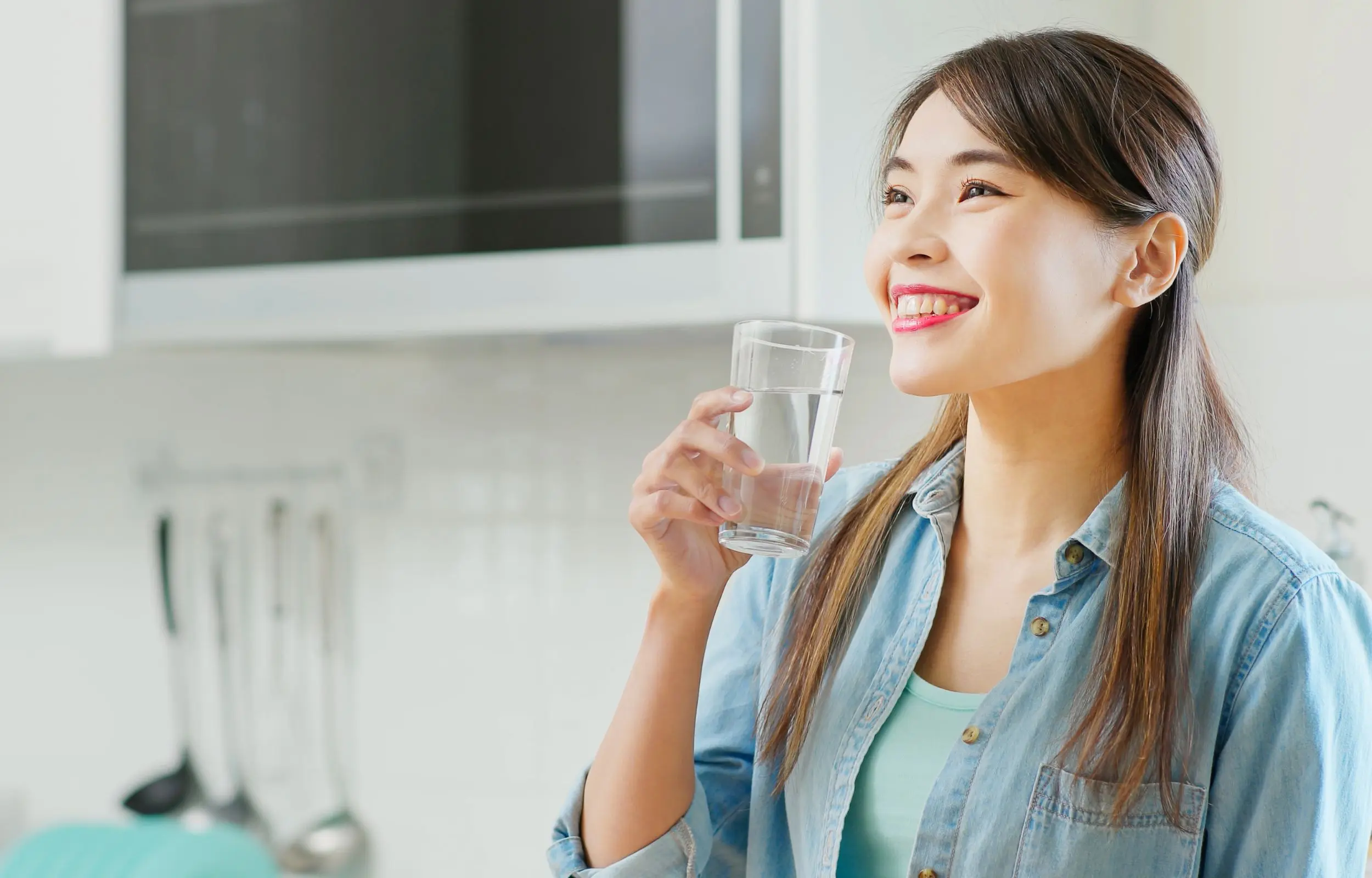 Happy woman holding a glass of water - H2O to GO